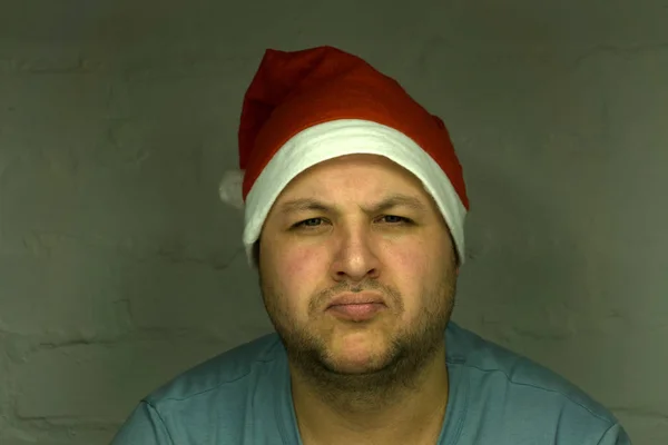 Santa en sombrero rojo muestra los pulgares hacia arriba. Santa Claus sostiene la bola de oro para abeto sobre fondo rojo. El hombre con barba y cara excitada se prepara para celebrar. Nochebuena y concepto de preparativos — Foto de Stock