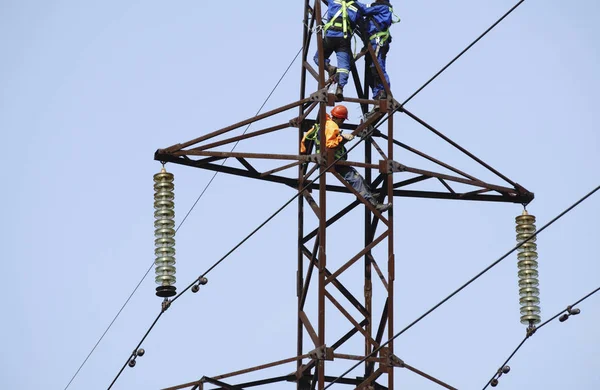 Güvenli bir şekilde ve sistematik olarak siluet elektrikçi çalışma yüksek gerilim yüksek gerilim istasyonlarında yüklemesini üzerinde doğal arka plan bulanık.