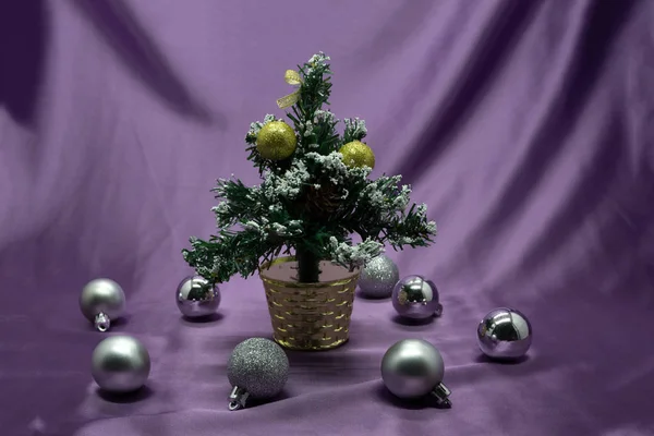 Un pequeño árbol de Navidad en una olla, decorado con bolas, guirnaldas y luces . — Foto de Stock