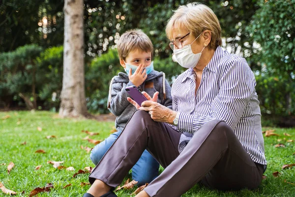 Mormor Och Barn Leker Med Smartphone Trädgården Samtidigt Som Bär — Stockfoto