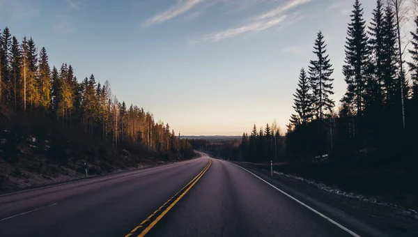 Finnische straße 4 e75 vor jyvaskyla, sonne steigt am horizont auf und die abfahrt macht eine klare sicht weit — Stockfoto