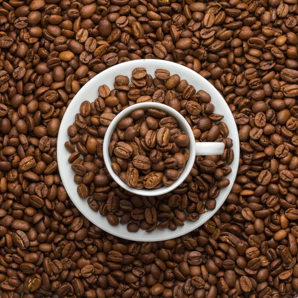 Kahve fincanı ve çay tabağı kahve taneleri ve rese ile dolu.