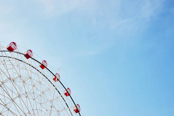 Ferris wheel with bright red booths on background of serene clea