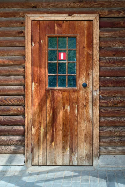 Red fire extinguisher logo plate on door of old wooden house as a safety and fire prevention measure in residential buildings. Concept of insurance and protection of housing from fire arson ignition.
