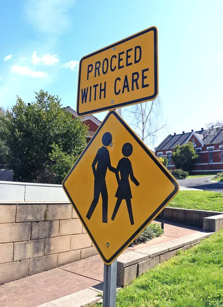 Yellow and black 'proceed with care' sign and aged care facility — Stock Photo, Image