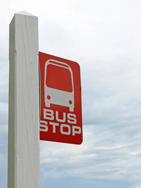 Vörös és fehér buszmegálló jelentkezzen újra egy kék-szürke viharos ég — Stock Fotó