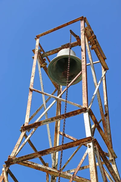 Campanile della chiesa e campanile arrugginito e catena in uno sfondo cielo blu — Foto Stock