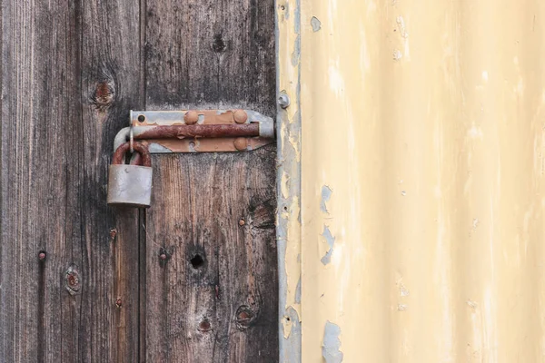 Perno candado oxidado en la puerta de madera vieja y cobertizo de hierro corrugado pintado Fotos De Stock Sin Royalties Gratis