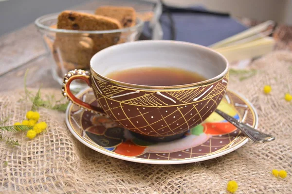 Tahta masada bir fincan siyah çay ve çikolatalı kurabiye.
