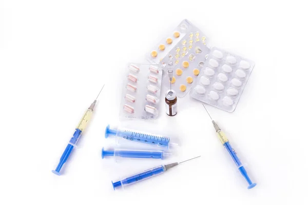Injektioner med nålar och tabletter mot den vita bakgrunden — Stockfoto