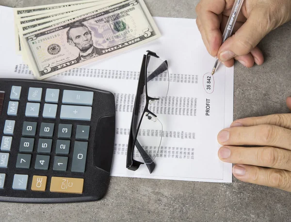 Profit and loss concept image of a pen, calculator and coins on financial documents.