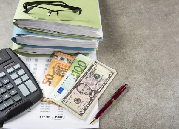 Profit and loss concept image of a pen, calculator and coins on financial documents.