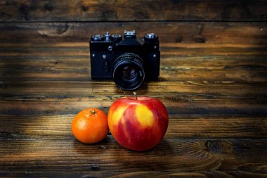 Film kamerası ahşap arka planda mandalina ve elma çekiyor
