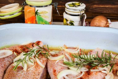 Tavada çiğ tavuk budu ve soğan.