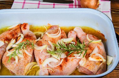 Tavada çiğ tavuk budu ve soğan.