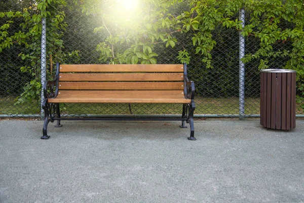 ゴミ箱付き公園内の空いている木製のベンチ — ストック写真