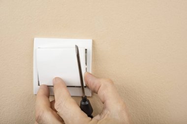 Duvarda beyaz elektrik düğmesi var ve kapağı yok.