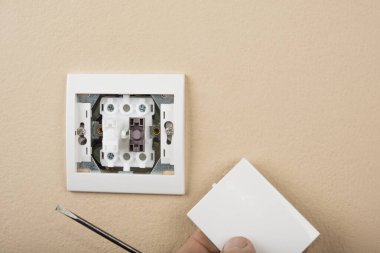 Duvarda beyaz elektrik düğmesi var ve kapağı yok.