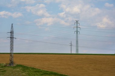Elektrik direkleri gökyüzü ile birlikte sahada