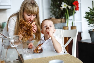 Anne ve oğlu mutfakta yemek vardır. Tarçın çocuğun burnunu çekmek