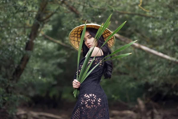 tropik bir ormanda hasır şapkalı genç seksi Vietnamca kız