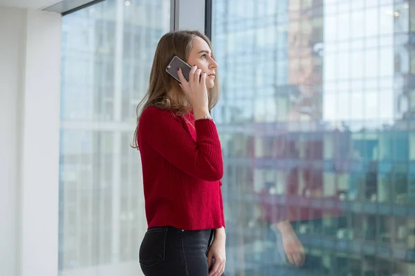 iş kadını pencereden bir parmağını gösterir ve telefonda konuşuyor. telefon görüşmeleri ve onay sonucu. yukarı başparmak 