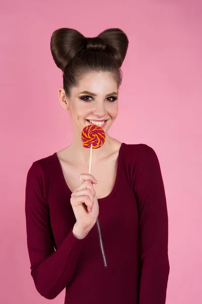 güzel kız bir sopa izole bir pembe arka plan üzerinde şeker yiyor. reklam için bir pudra Dükkanı