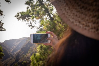 Genç bir kız cep telefonuyla manzarayı fotoğraflıyor.