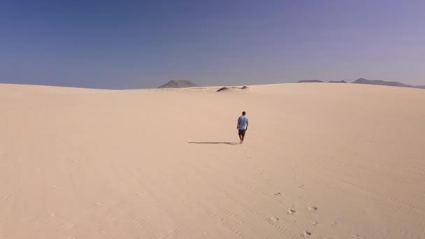 Ung man går längs sanden i den brännande solens strålar, fuerteventura — Stockvideo