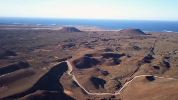 Vue aérienne d'une route menant à travers une vaste zone de terres volcaniques et de montagnes — Video