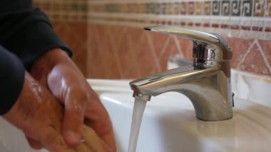 Adam ellerini sabunla yıkıyor.