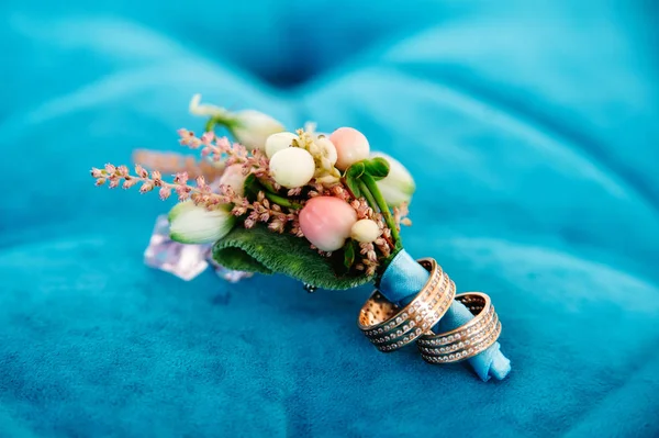 Boutonniere con dos anillos de boda sobre fondo azul — Foto de Stock