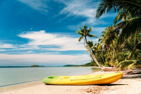 Tropical beach with curved palm trees and yellow canoe — Stock Photo, Image