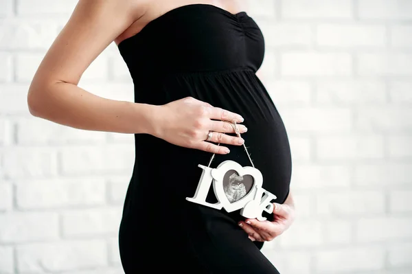 Pregnant woman is holding ultrasound scan on her belly. — Stock Photo, Image