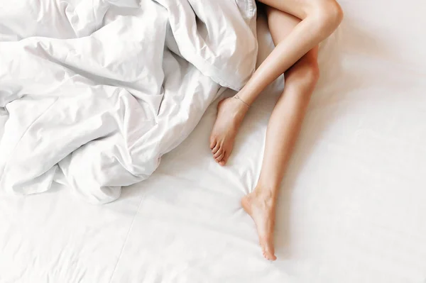 Slim, perfect and beautiful crossed woman legs on bed. Royalty Free Stock Photos