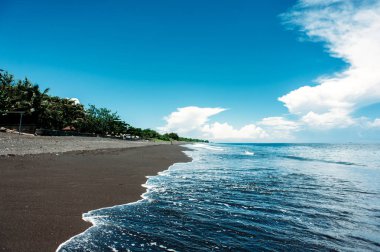Siyah volkanik kum, mavi gökyüzü bulutlu olan tropikal alışılmadık egzotik plaj.