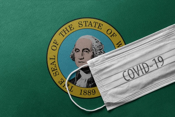 An individual face medical surgical mask on Washington State Flag Background. Health mask. Protection against COVID-19 virus, influenza, SARS. Coronavirus in Washington