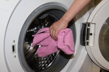 Kadın elleri havluyu wahing makinesine yüklüyor.. 