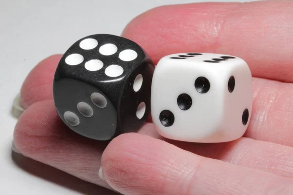 Two dice in hand on a white background. White and black dice in hand on a white background. Isolated dice close up.