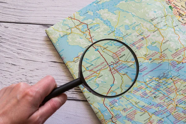 Magnifying glass and map on the wooden background