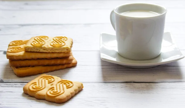 Cup of milk and cookie on a wooden background. Healthy breakfast.