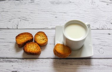Tahta arka planda bir fincan süt ve ekmek kırıntısı. Sağlıklı kahvaltı..