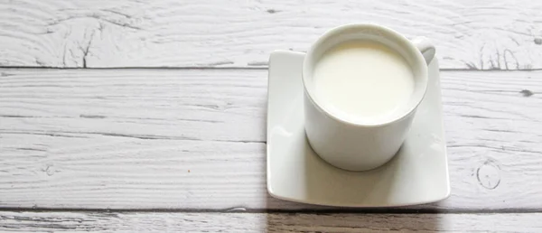 Cup of warm milk on a wooden background. White Cup with milk.