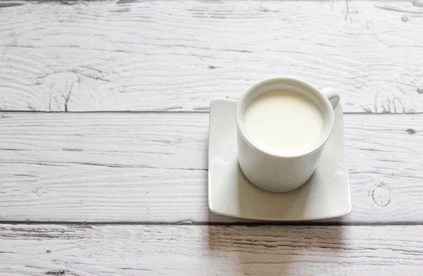 Kopp varm mjölk på en trä bakgrund. Vit kopp med mjölk. — Stockfoto
