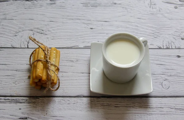 Xícara de leite e breadstick em um fundo de madeira. Café da manhã saudável . — Fotografia de Stock