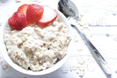 Tahta arka planda taze çilekli yulaf lapası..