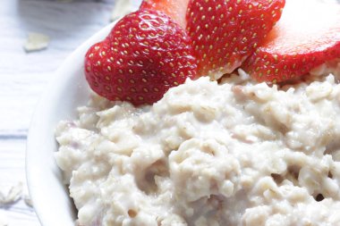 Tahta arka planda taze çilekli yulaf lapası..