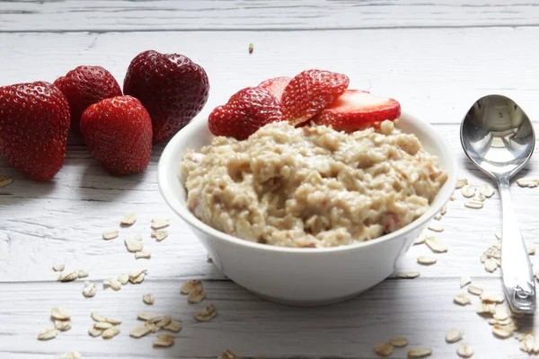 Haferbrei mit frischen Erdbeeren auf einem hölzernen Hintergrund. — Stockfoto