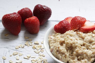 Tahta arka planda taze çilekli yulaf lapası..
