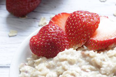 Tahta arka planda taze çilekli yulaf lapası..